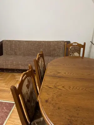 a wooden table and chairs in a living room with a couch at Stan in Niš