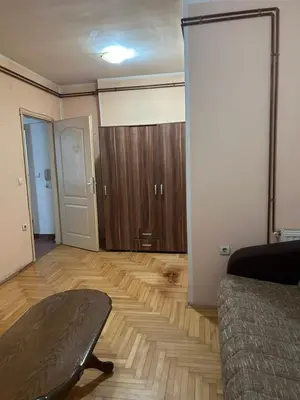 a living room with a bed and a wooden floor at Stan in Niš