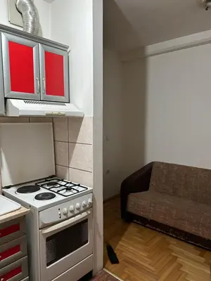 a kitchen with a stove and a living room with a couch at Stan in Niš