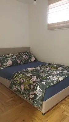 a bed in a bedroom with a floral bedspread at Apartman Boki X in Vrnjačka Banja