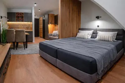 a bedroom with a large bed and a dining room at Apartman Stagira - Bela Reka Gondola, Kopaonik in Brzeće