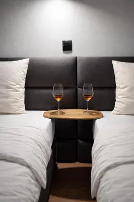 two glasses of wine on a table between two beds at Apartman Stagira - Bela Reka Gondola, Kopaonik in Brzeće