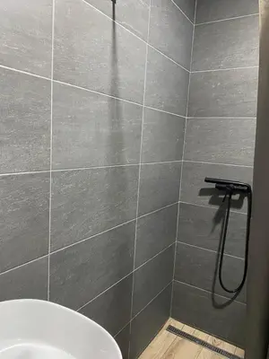a bathroom with a gray tiled wall with a shower at Mountain Soul - Residence Hill in Kopaonik