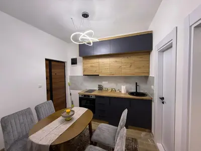 a kitchen with a wooden table and chairs and a kitchen with a sink at Apartman Djurdja in Raška