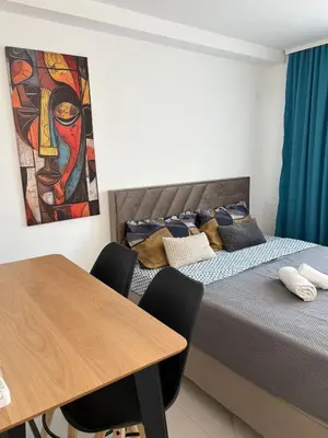 two beds in a room with a table and a painting at Nik 2 in Kruševac