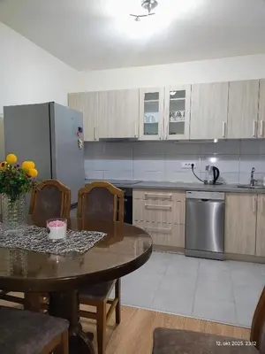 a kitchen with a table and a stainless steel refrigerator at Apartman Novak in Trnava