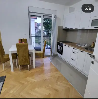a kitchen with white cabinets and a table with a dining room at Apartmani Vrnjacka Banja 8 in Vrnjci