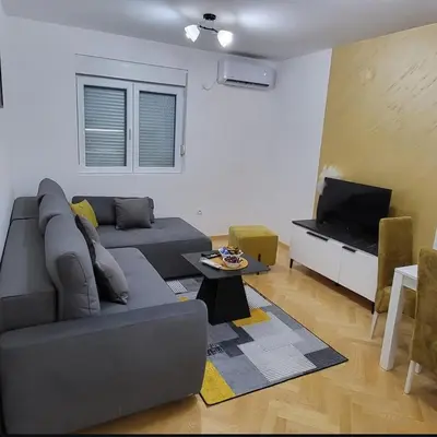 a living room with a gray couch and a tv at Apartmani Vrnjacka Banja 8 in Vrnjci