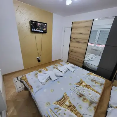 a bedroom with a large bed with a tv on the wall at Apartmani Vrnjacka Banja 8 in Vrnjci