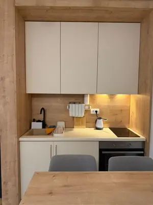 a kitchen with white cabinets and a table with chairs at Apartman Vrnjacka Banja in Vrnjci