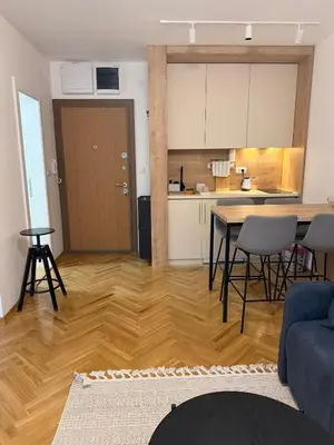 a living room with a table and a kitchen at Apartman Vrnjacka Banja in Vrnjci