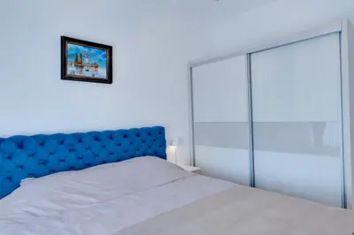 a bed with a blue headboard in a bedroom at Portofino in Vrnjačka Banja