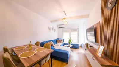 a living room with a table and a blue couch at Portofino in Vrnjačka Banja