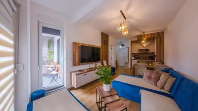 a living room with a blue couch and a kitchen at Portofino in Vrnjačka Banja