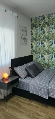 a bedroom with a bed with a green leafy wall at Luna Apartmani in Soko Banja