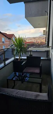 a balcony with a chair and a table and a plant at Luna Apartmani in Soko Banja