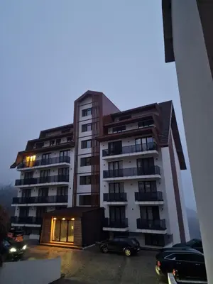 a large building with cars parked in a parking lot at Whisper apartments Kopaonik in Kopaonik