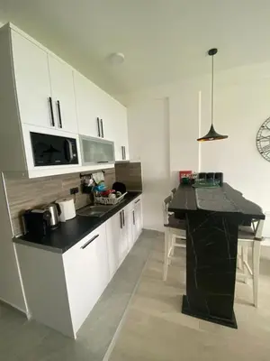 a kitchen with white cabinets and a black counter top at Pahuljica - N25 Milmari in Raška