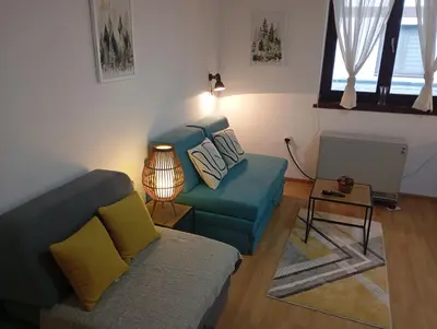 a living room with a blue couch and a table at Bela reka Gondola Studio in Brzeće