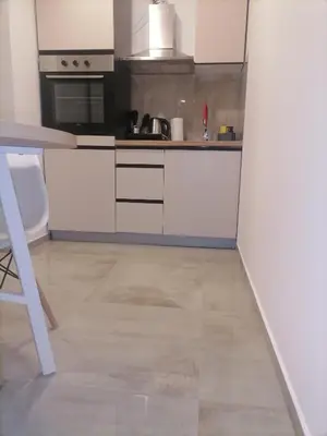 a kitchen with white cabinets and a tile floor at Cloud in Niš