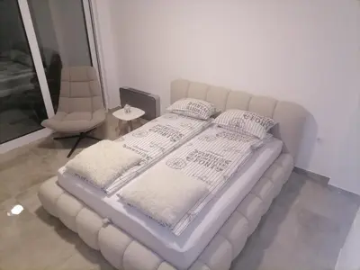 a white bed with pillows and a chair in a room at Cloud in Niš