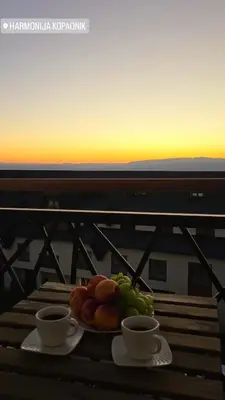 a plate of fruit sitting on a table with two cups at Apartman Harmonija in Kopaonik