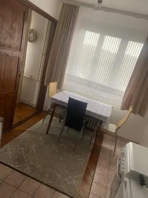 a table and chairs in a room with a window at Apartman Mina in Kuršumlija