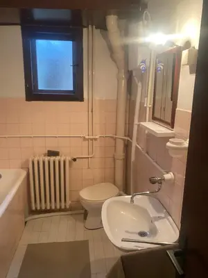 a bathroom with a sink and a toilet and a window at Apartman Mina in Kuršumlija