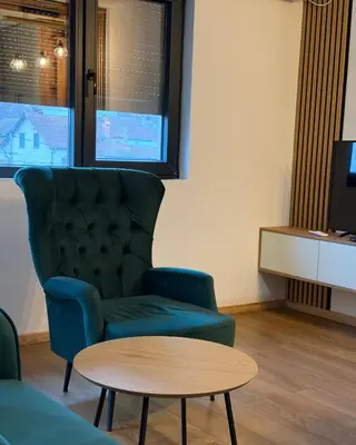 a living room with a chair and a table at Emerald Residence in Vrnjačka Banja