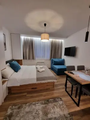 a bedroom with a large bed and a blue couch at SKYLINE apartments Kopaonik in Kopaonik