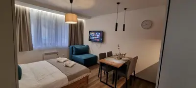 a bedroom with a bed and a table and a chair at SKYLINE apartments Kopaonik in Kopaonik