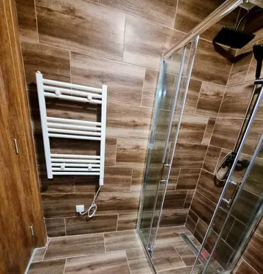 a bathroom with a shower with a wooden floor at SKYLINE apartments Kopaonik in Kopaonik