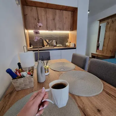 a person sitting at a table with a cup of coffee at SKYLINE apartments Kopaonik in Kopaonik