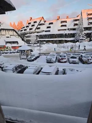 a parking lot covered in snow with parked cars at Centar slope apartman in Kopaonik