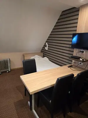 a room with a desk with chairs and a bed at Cetar slope 2 apartman in Kopaonik