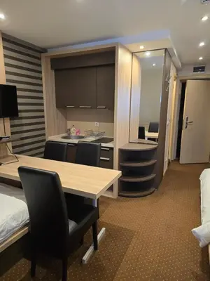a room with a bed and a table and chairs at Cetar slope 2 apartman in Kopaonik