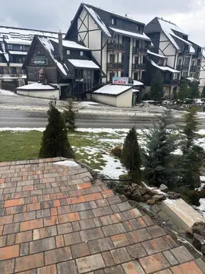 a brick walkway in front of a building with christmas trees at Apartman u hotelu Harmonija Palace Kopaonik in Kopaonik