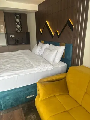 a bedroom with a large bed and a yellow couch at Apartman u hotelu Harmonija Palace Kopaonik in Kopaonik