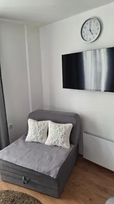 a couch in a room with a clock on the wall at Apartmani Maša Kopaonik in Kopaonik