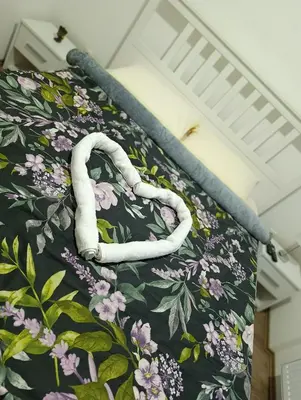 a bed with a floral bedspread with a swan on it at Apartman AURORA Trstenik in Trstenik