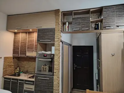 a kitchen with wooden cabinets and a black door at Ski in ski out Apartman in Kopaonik