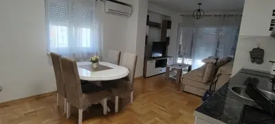 a kitchen and living room with a white table and chairs at Apartman CiricMDV in Vrnjci