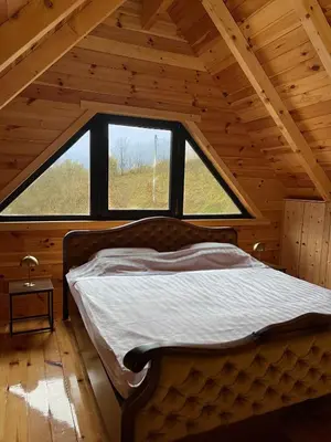 a bed in a room with a large window at Kaizen Cabin in Kursumlijska Banja
