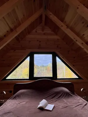 a bed in a room with a large window at Kaizen Cabin in Kursumlijska Banja