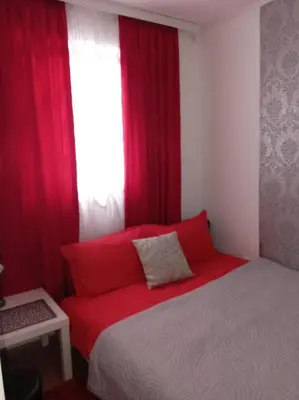 a bed with red pillows in a room with a window at Apartmani NANA in Vrnjci