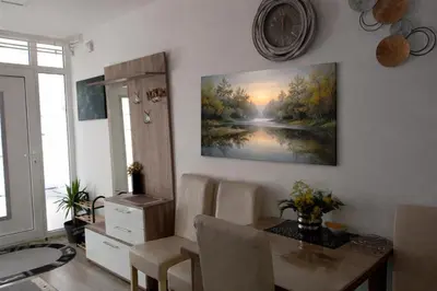 a dining room with a table and a painting on the wall at Apartmani NANA in Vrnjci