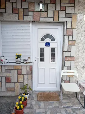 a white door on a brick wall with flowers and plants at Apartmani NANA in Vrnjci