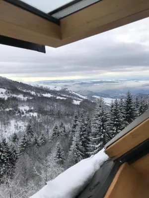a room with a view of a snow covered forest at Chalet Pinecone - Ušuškan apartman, savršen za zimu i leto - Modern Mountain Retreat with Stunning View in Kopaonik