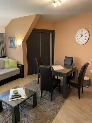 a living room with a table and chairs and a clock at Apartment Brvenik Plus in Kopaonik