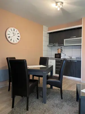 a dining room with a table and chairs and a clock at Apartment Brvenik Plus in Kopaonik